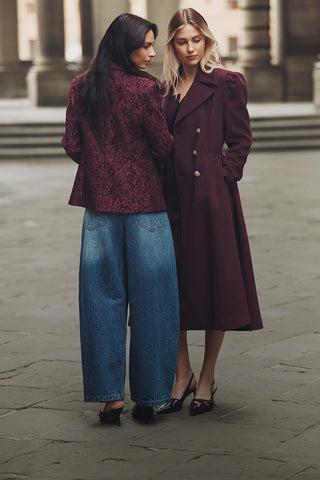 Dos mujeres sonriendo frente a un edificio moderno, luciendo ropa casual y disfrutando del momento