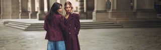 Dos mujeres sonriendo frente a un edificio moderno, luciendo ropa casual y disfrutando del momento