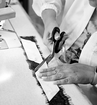 Image of a seamstress's hands cutting a lace trim